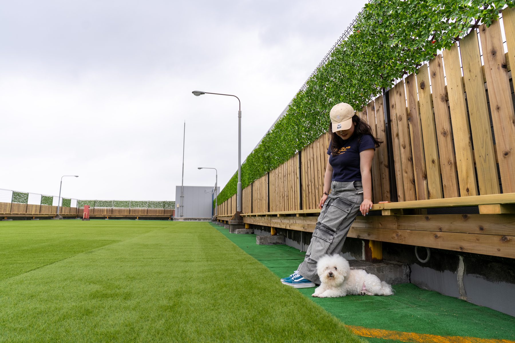 屋上のフェンス際で犬と寄り添う利用者